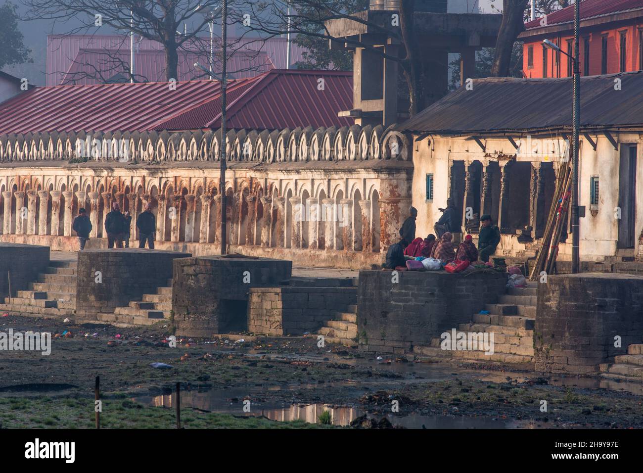 Menschen am frühen Morgen über den stark verschmutzten Bagmati-Fluss im Pashupatinath-Tempelkomplex in Kathmandu, Nepal. Stockfoto