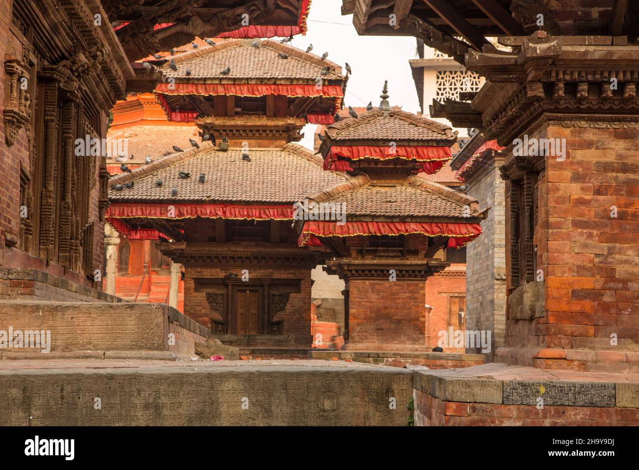 Die Inschriftenwand im Vordergrund einer Gruppe kleiner Hindu-Tempel auf dem Durbar-Platz, Kathamandu, Nepal. Stockfoto