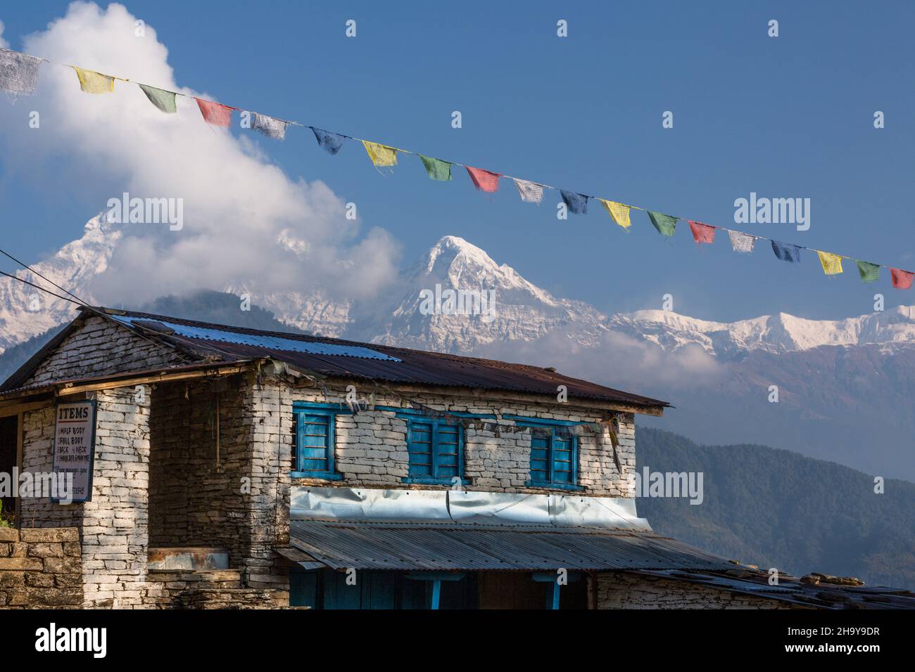 Ein traditionelles nepalesisches Bauernhaus im Himalaya-Vorgebirgsdorf Dhampus, Nepal. Im Hintergrund sind Annapurna South und Hiunchuli im HIM zu sehen Stockfoto