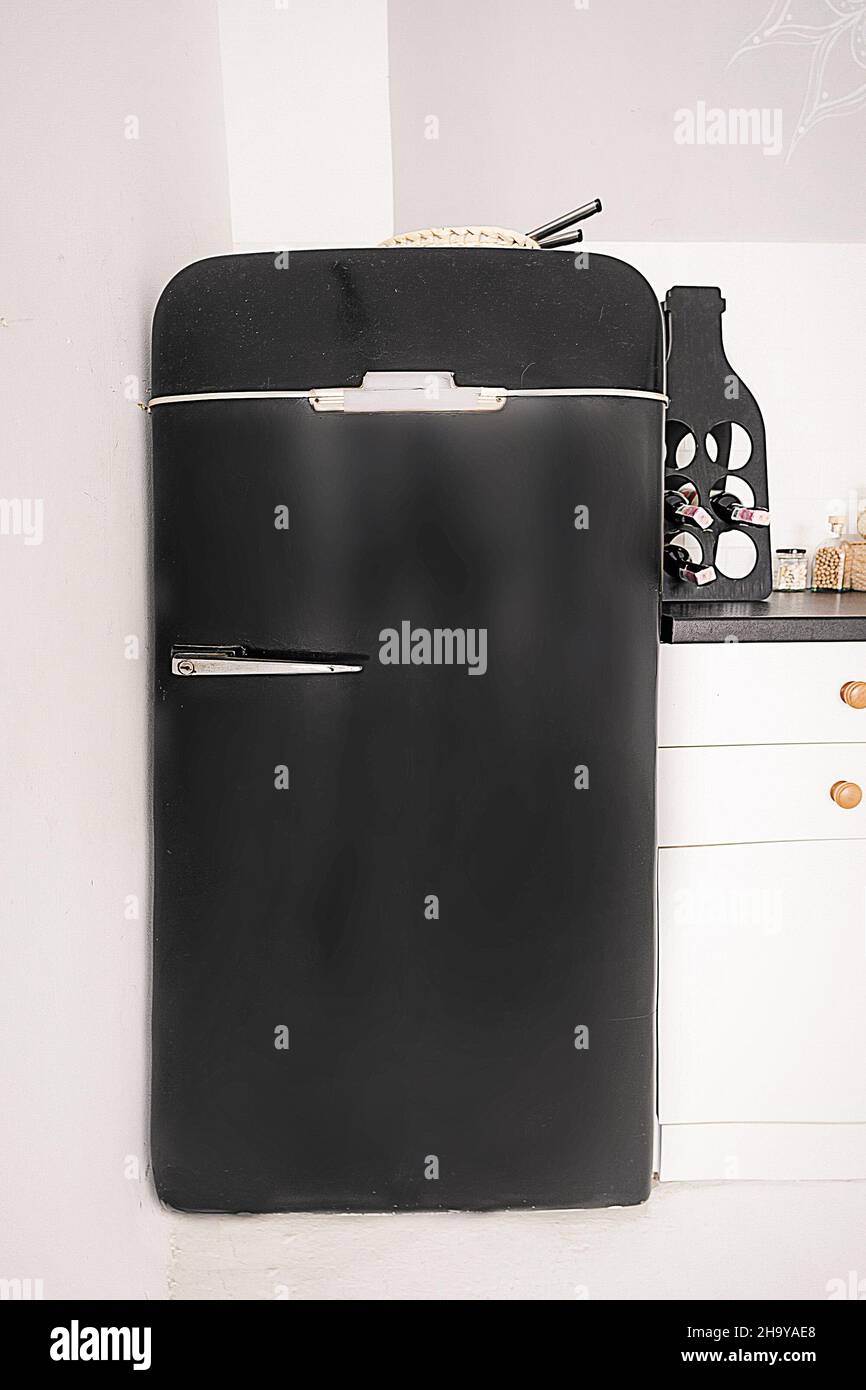 Kleiner schwarzer Retro Kühlschrank in weißer Küche, schwarzer Kühlschrank im Vintage-Stil auf weißem Hintergrund. Nahaufnahme. Hochwertige Fotos Stockfoto
