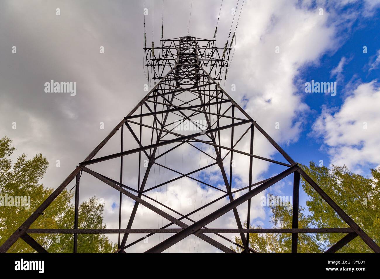 Hochspannungsausrüstung gegen den blau bewölkten Himmel. Strompylon gegenüber dem blauen Himmel. Stockfoto