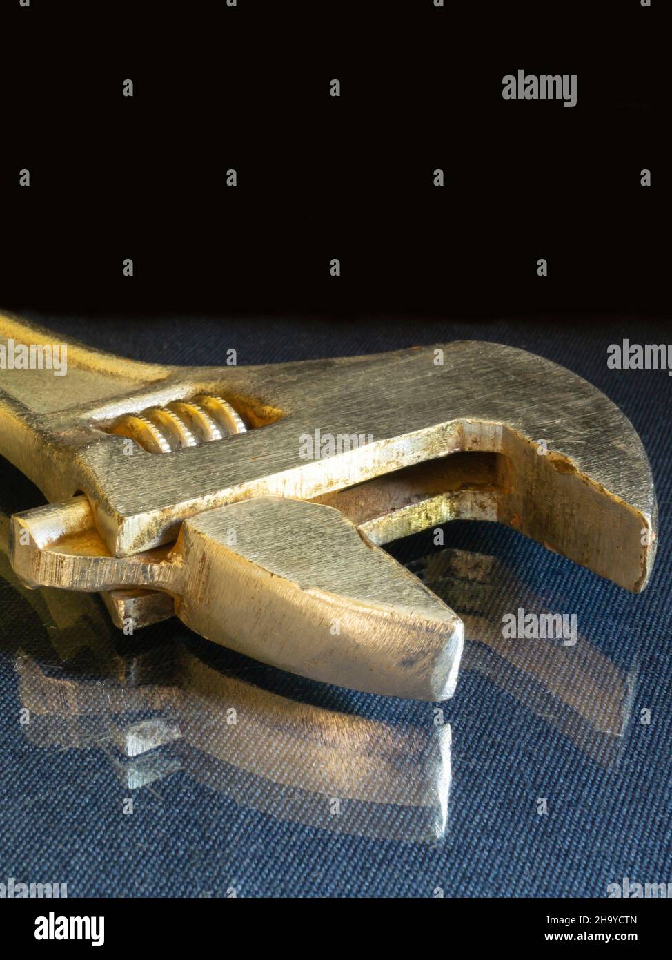 Der Schraubenschlüssel ruht auf einem Glastisch auf schwarzem Hintergrund. Das Instrument zur Befestigung der Details. Stockfoto