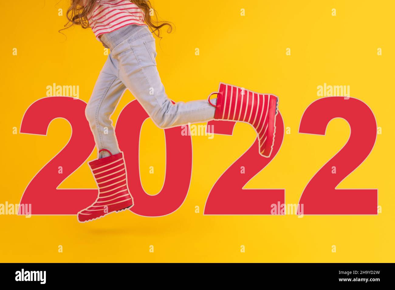 2022 Konzept des Mädchens mit roten Gummistiefeln für Regen auf gelbem Hintergrund Stockfoto