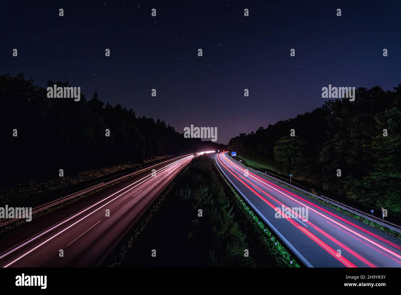 Eine deutsche Autobahn bei Nacht mit Lichtspuren der schnell fahrenden Autos in rot, Hintergrundbild für ein Hochgeschwindigkeitskonzept. Stockfoto