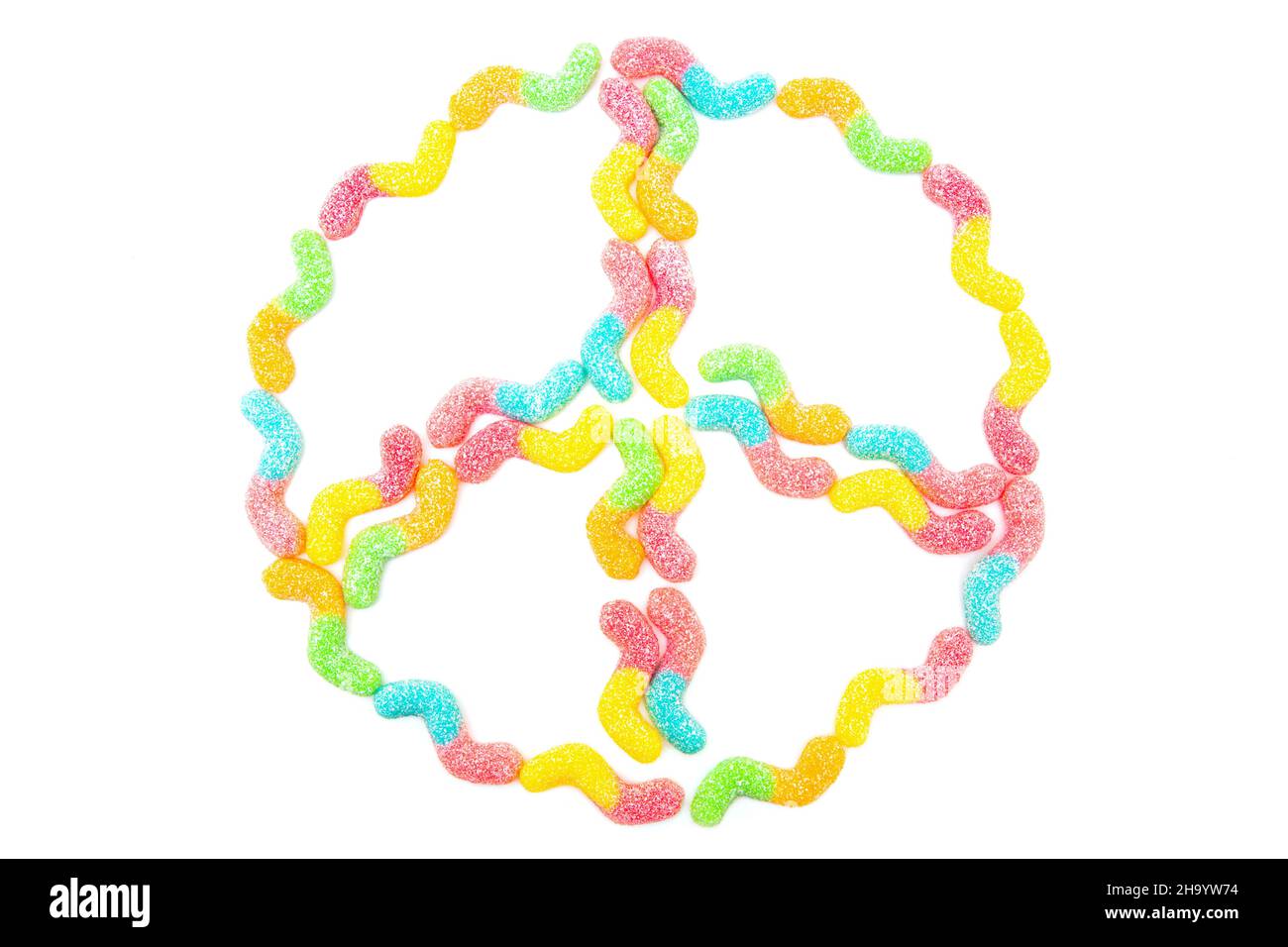 Friedenssymbol aus mehrfarbigen, mit Zucker überzogenen Gummiwürmern, die auf Weiß isoliert sind. Konzept der Antikriegsbewegung. Stockfoto