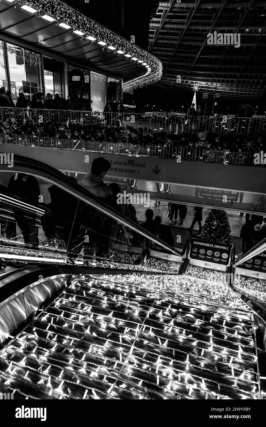 Paris, Frankreich - 18. Dezember 2021: Einkaufsbummel auf Rolltreppen im Einkaufszentrum Westfield Forum des Halles während der Winterurlaubsverkäufe. Schwarzweißfoto Stockfoto