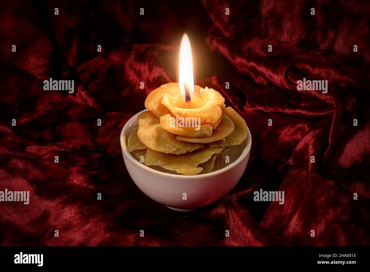 Natürliche Wachskerze in Form einer Rose auf rotem Samthintergrund Stockfoto