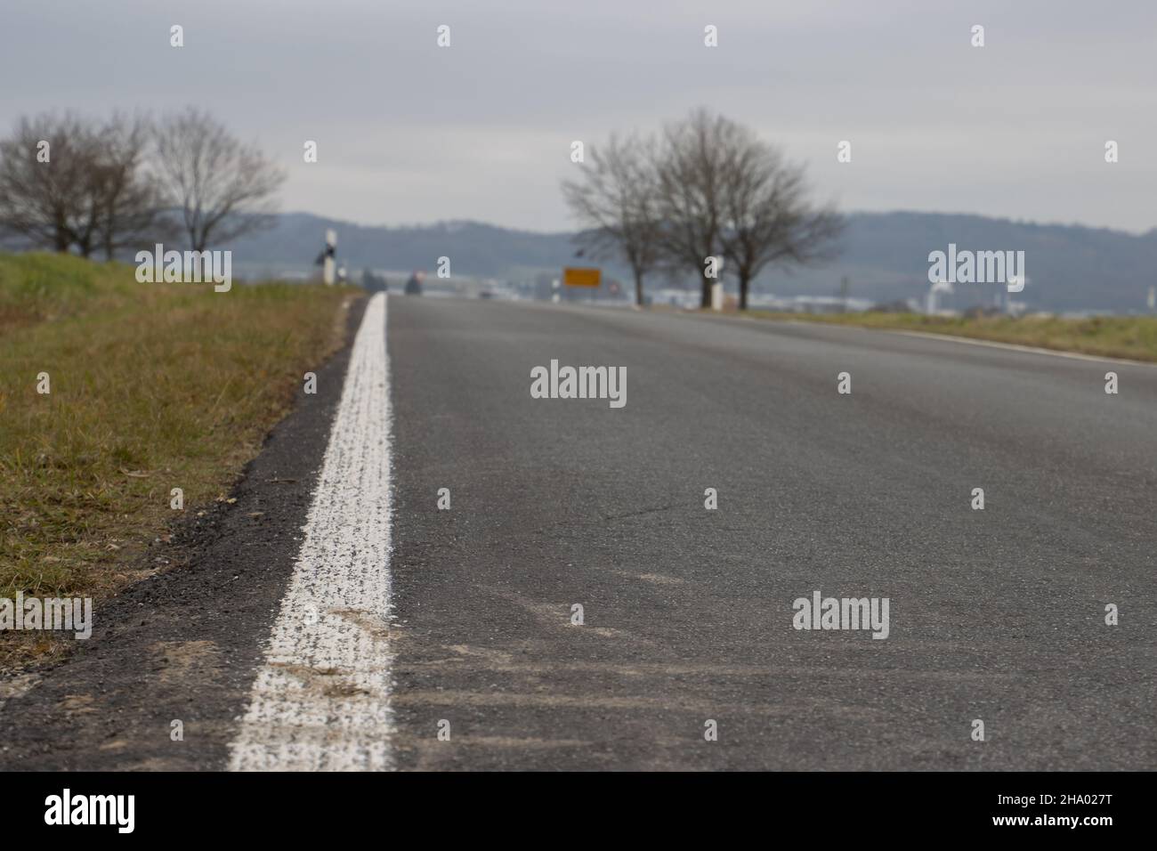 Kleine Landstraße mit weißen Markierungen an der Seite mit Fokus im Vordergrund Stockfoto