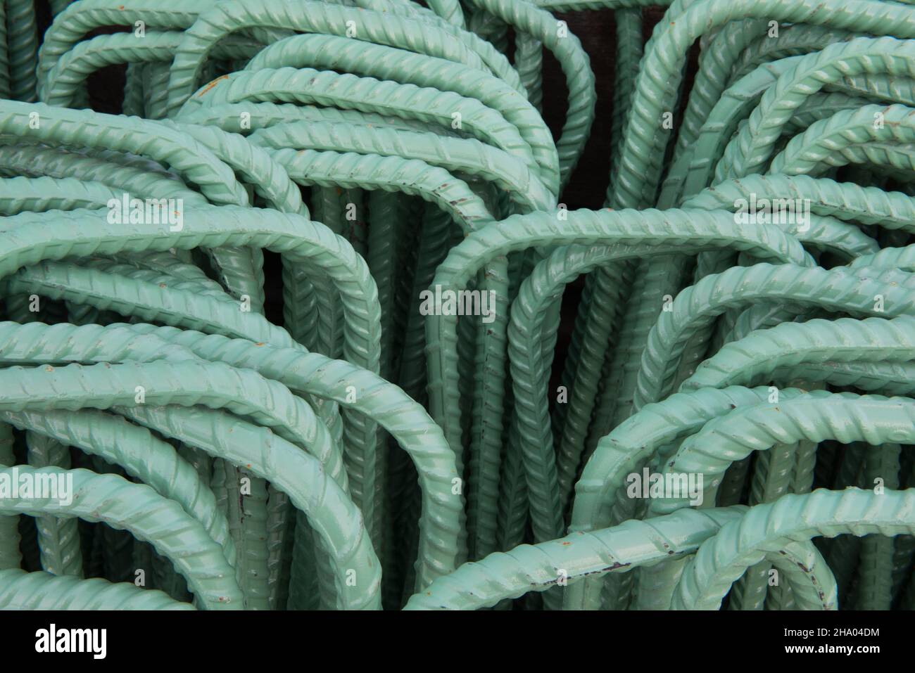 Ein Sortiment an per-fabricated rebar mit einer grünen Epoxid-Beschichtung für Korrosionsbeständigkeit ist bereit für die Installation in einem Infrastrukturprojekt. Stockfoto