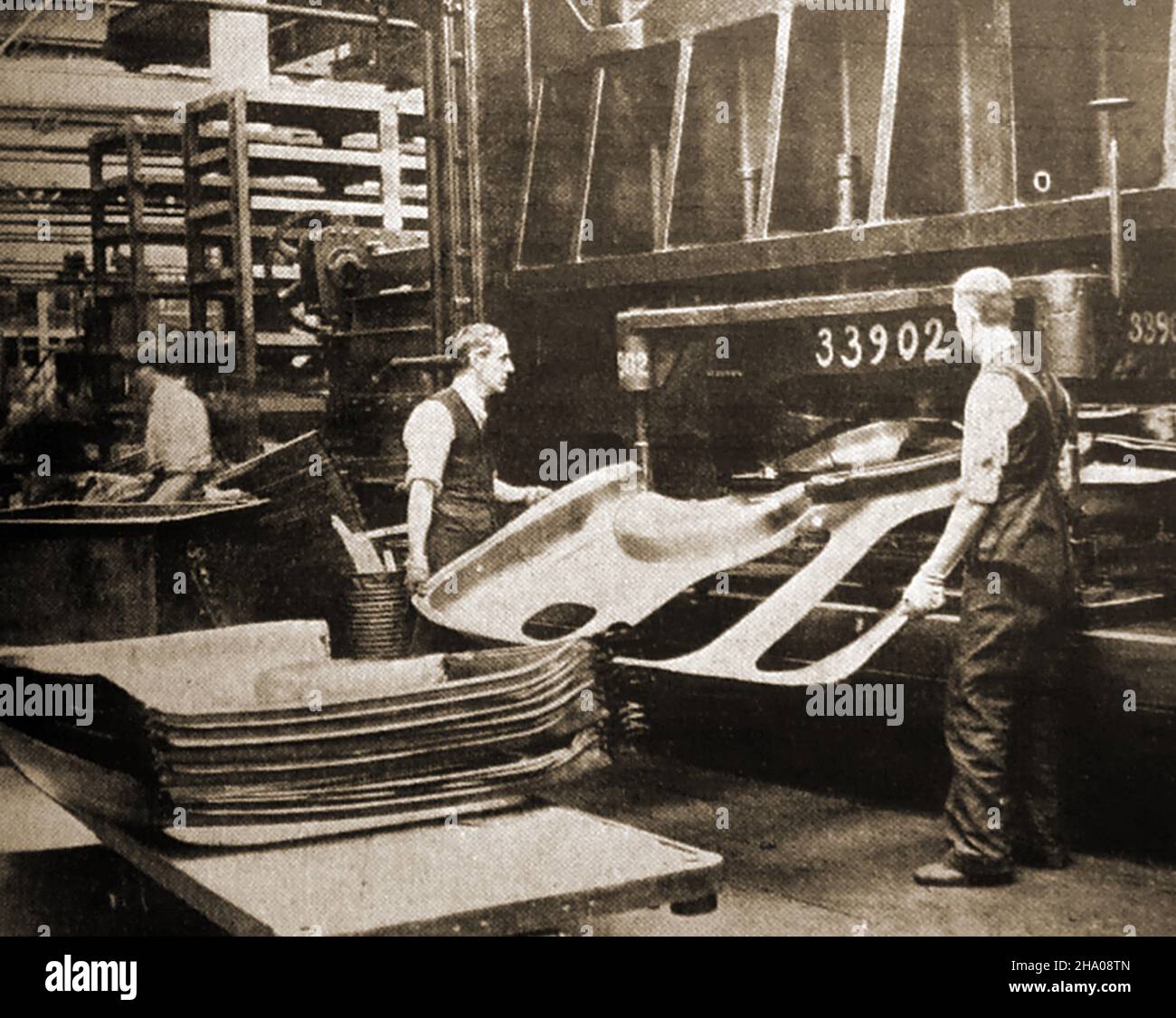 Ein frühes Foto von Arbeitern, die in einer britischen Automobilfabrik Karosserieteile aus Blech pressen Stockfoto