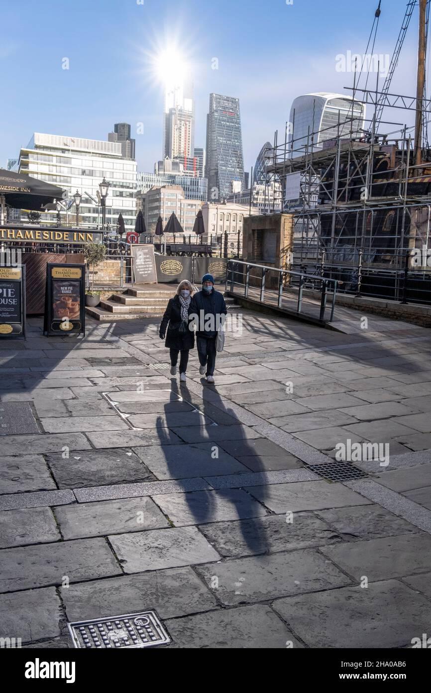 Fußgänger am St Mary Overie gehen am 9th. Dezember 2021 in London, England, durch das Sonnenlicht auf der Bankside in Southwark. Stockfoto