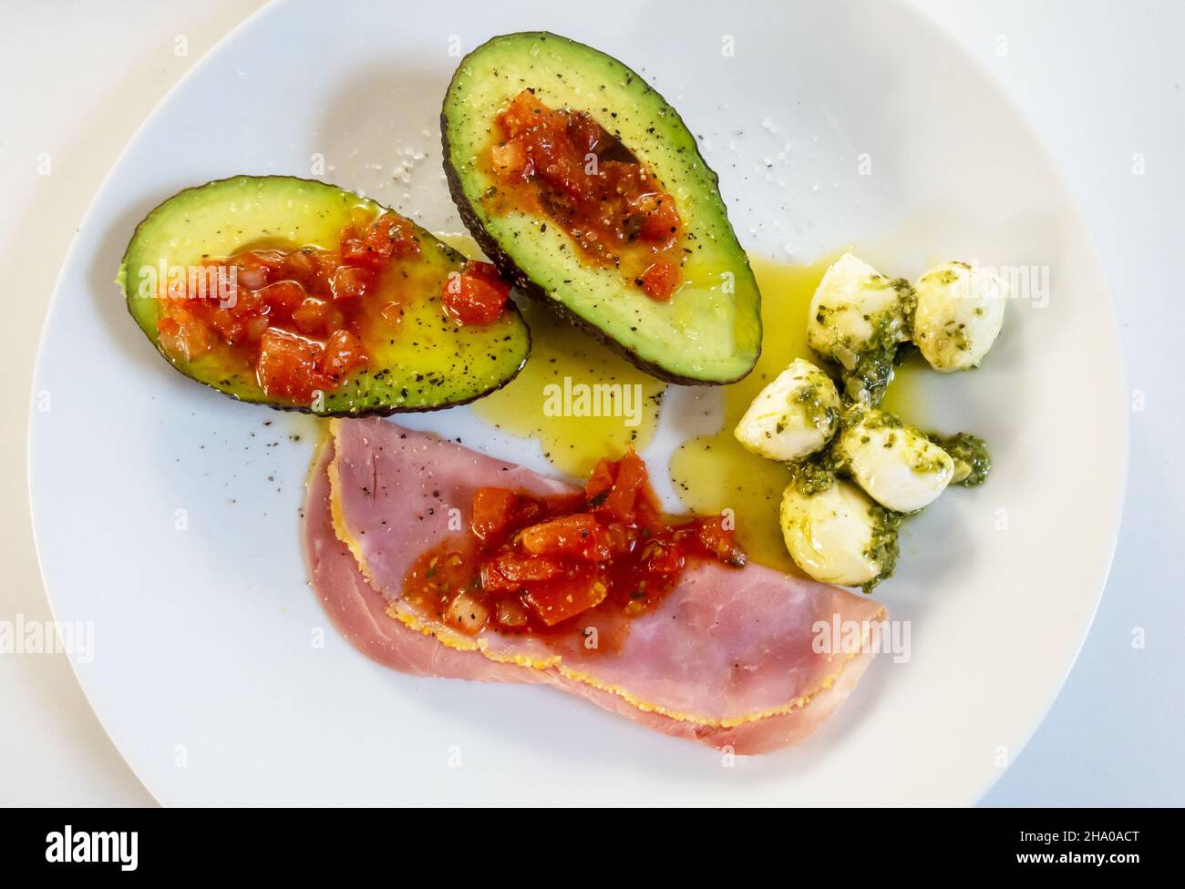 Antipasti mit Avocado-Essig, Mozzarella-Kugeln, Schinken und Tomatensalsa gemischt Stockfoto