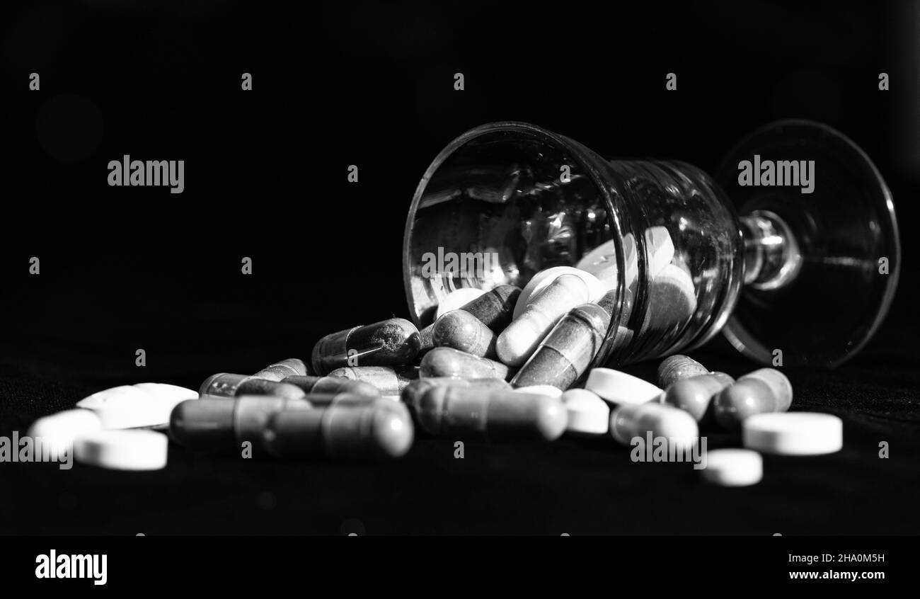 Gelatinekapsuless und Tabletten Pharmazeutika aus gefallener Glas dunklen Hintergrund, Pillen Stockfoto