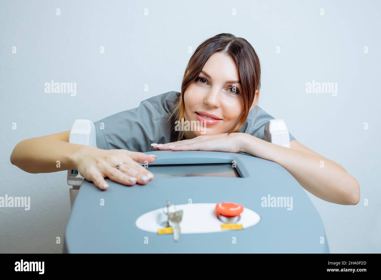 Die Kosmetologin in einem medizinischen Mantel hält einen Teil des modernen Laserepilierers in der Hand und posiert für ein Foto. Behandlung der Laserepilation Stockfoto