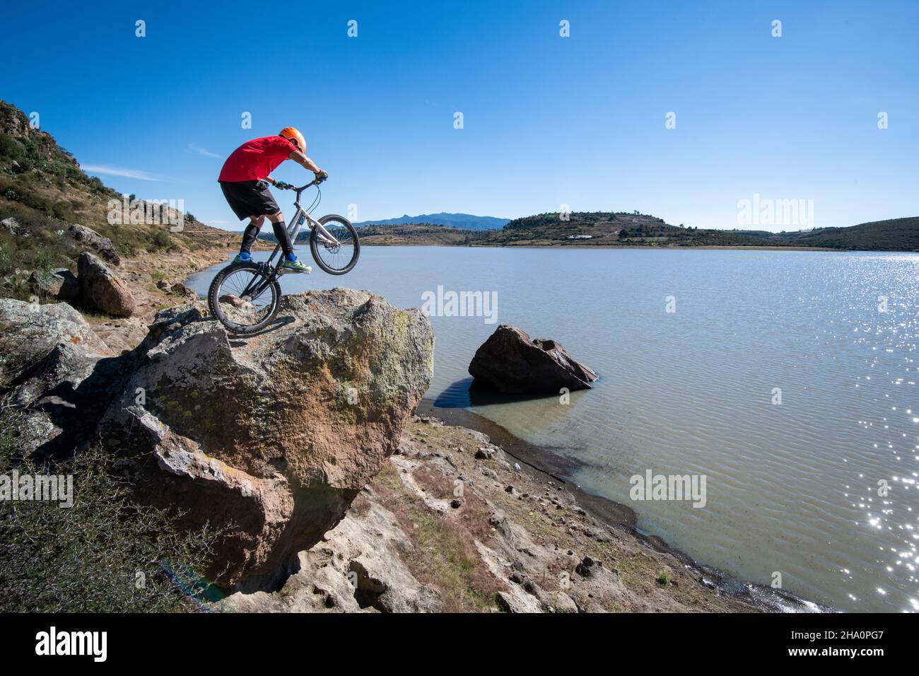 Ein Mann balanciert auf einem Felsen mit Hinterrad auf dem Trial Bike Stockfoto