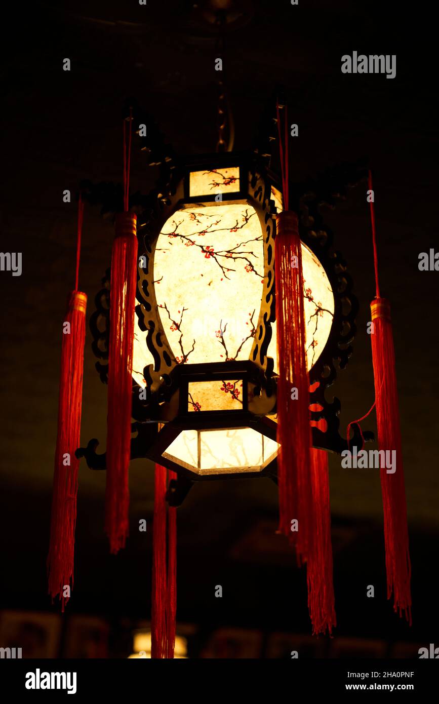 Asiatisch inspirierte Lampe, die in einem dunklen Raum hängt Stockfoto