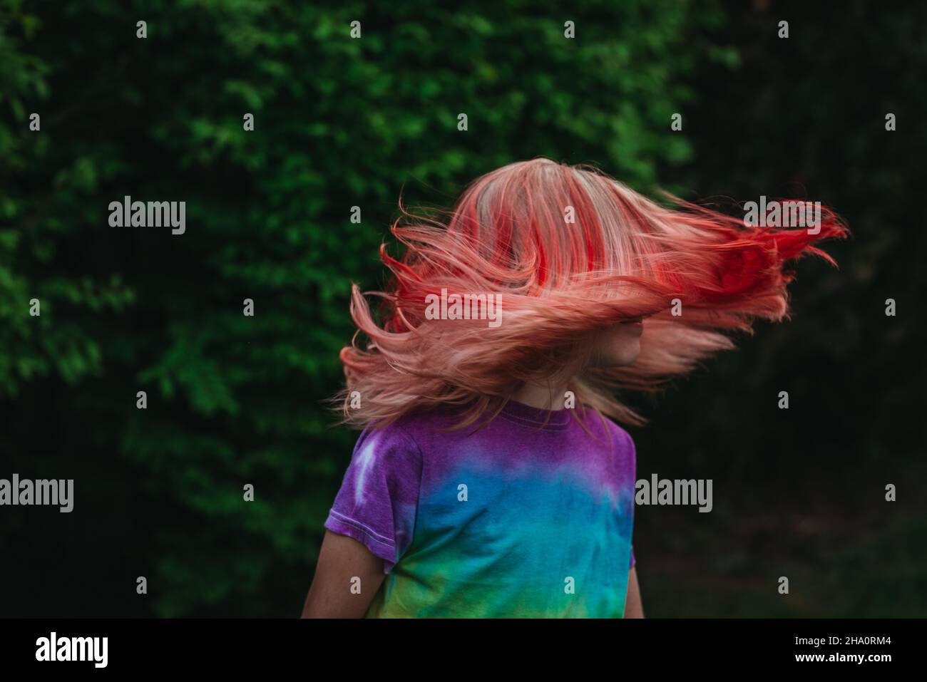 Junges Mädchen schüttelt die Haare draußen mit gefärbten roten Haaren Stockfoto