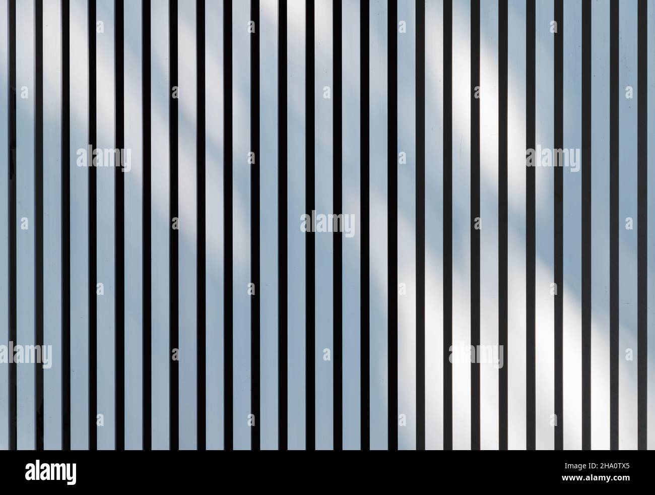 Das Muster der weichen Schatten liegt über dem weißen Metallzaun. Hintergrundfotostruktur Stockfoto