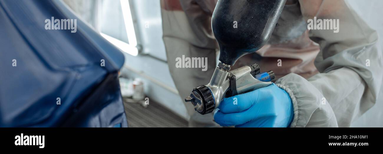 Banner . Automobil-Werkstatt Maler Hand in Schutzhandschuh mit Airbrush Pulverisator Malerei Auto Körper in Farbkammer. Stockfoto