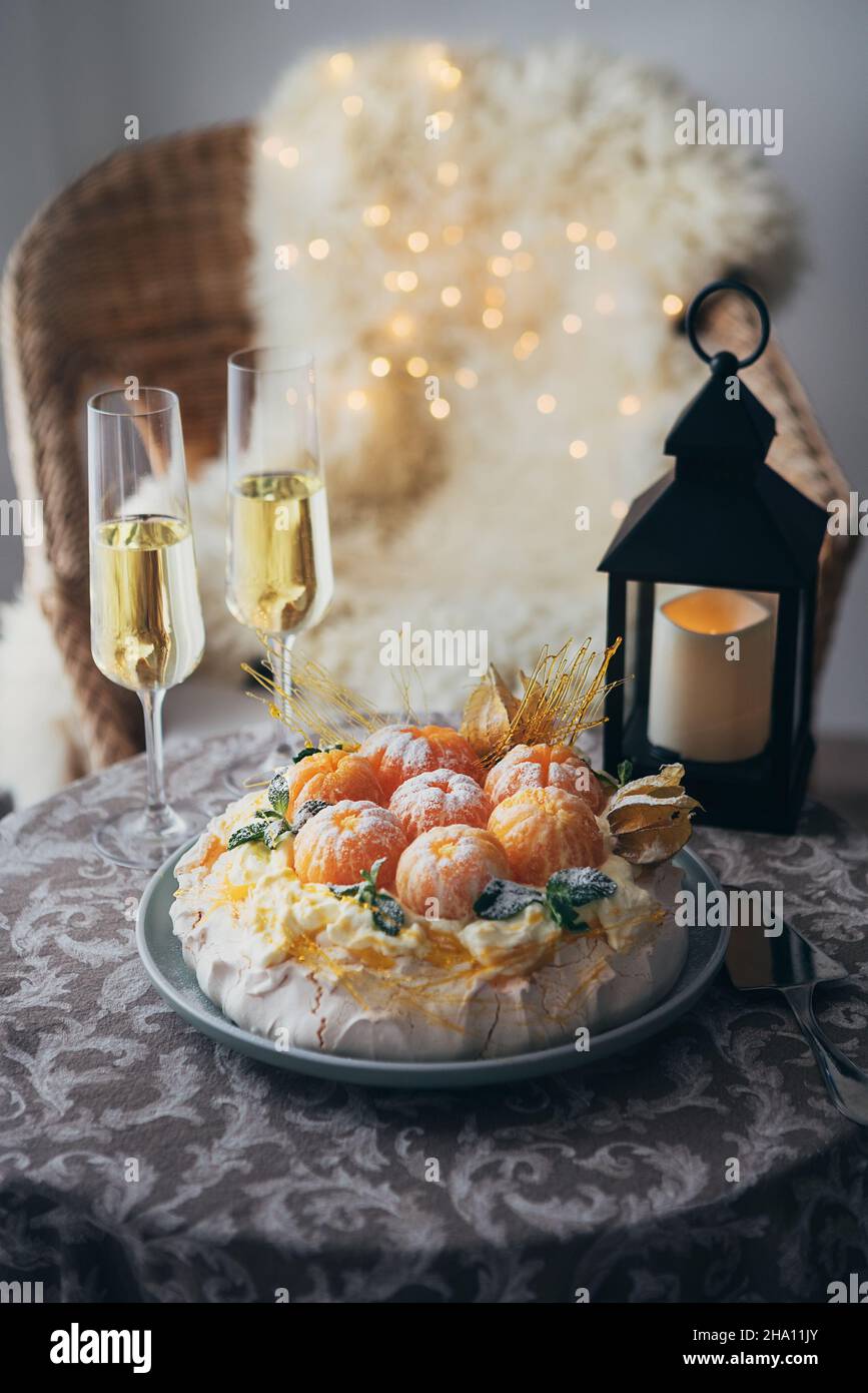 Pawlova-Dessert auf Basis von Baiser, benannt nach russischer Ballerina, dekoriert mit frischen Mandarinen, Karamell, Physalis und Puderzucker mit zwei champa Stockfoto