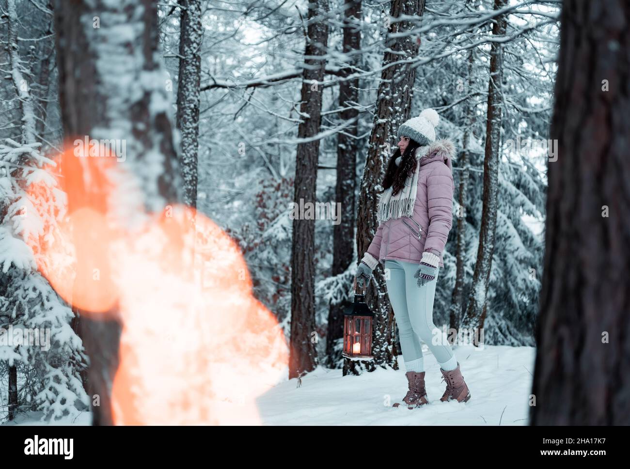 Das Mädchen hält eine Laterne mit einem Licht in der Hand und leuchtet auf ihrem Weg in den gefrorenen Wald, Weihnachten und gefrorene Atmosphäre, Bethlehem Licht leuchtet ich Stockfoto