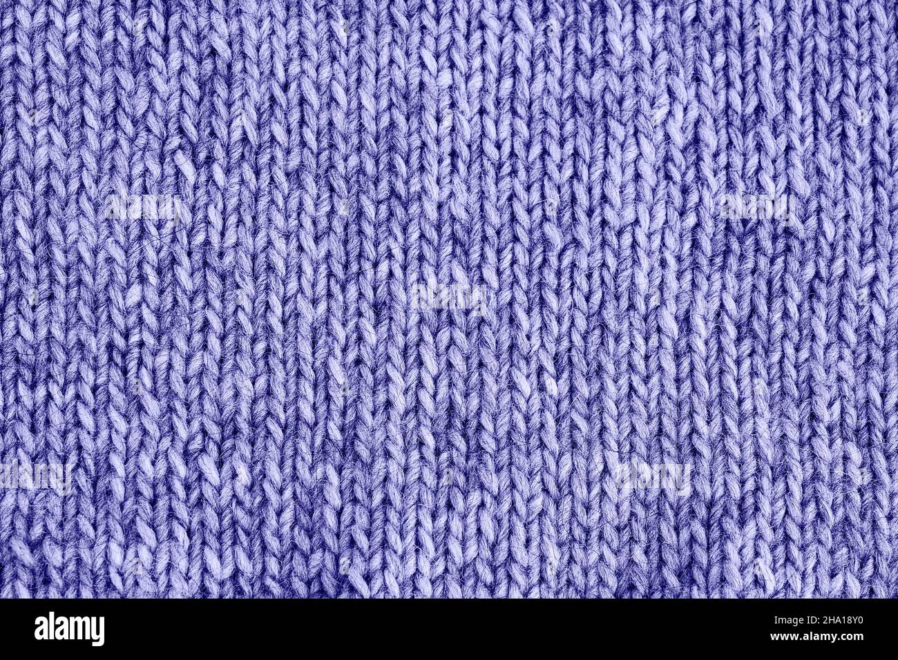 Flieder sehr peri gestrickte Textur. Handgefertigte Strickmode. Farbe des Jahres 2022 sehr peri getönt. Abstrakter Hintergrund, Kopierbereich. Stockfoto