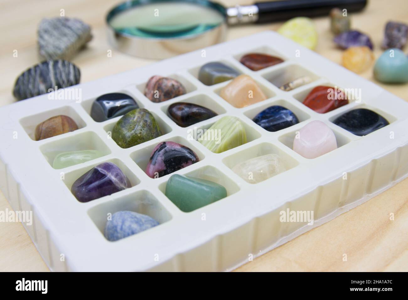 Box mit einer Sammlung von Mineralien mit Halbedelsteinen neben einer Lupe Stockfoto