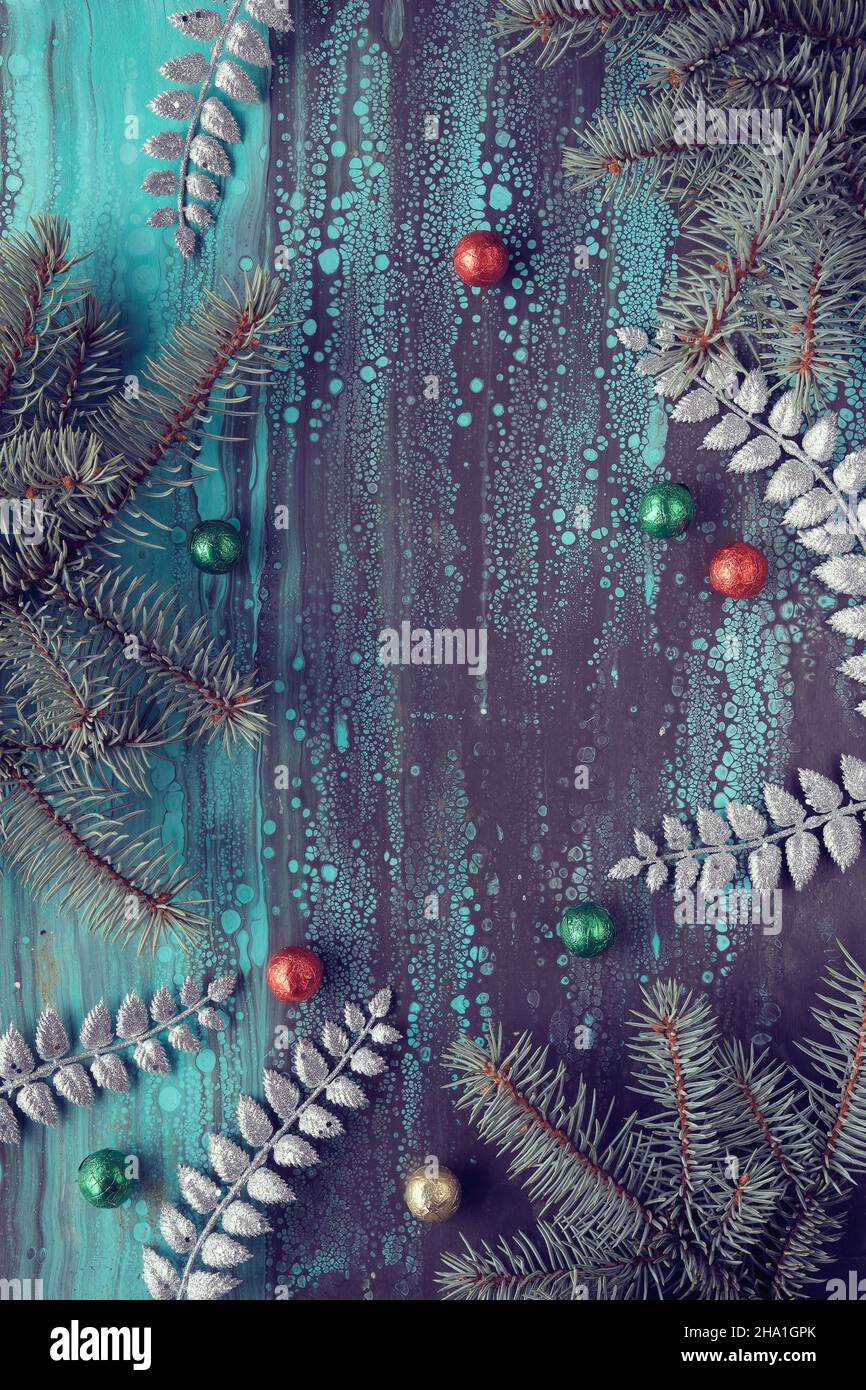 Silberner Weihnachtsrand mit Tannenzweigen und Schokoladen-Süßigkeiten-Kugeln in roter, grüner und gelber Folie. Copy-Space, für Text platzieren. Acryl Hintergrund in Stockfoto