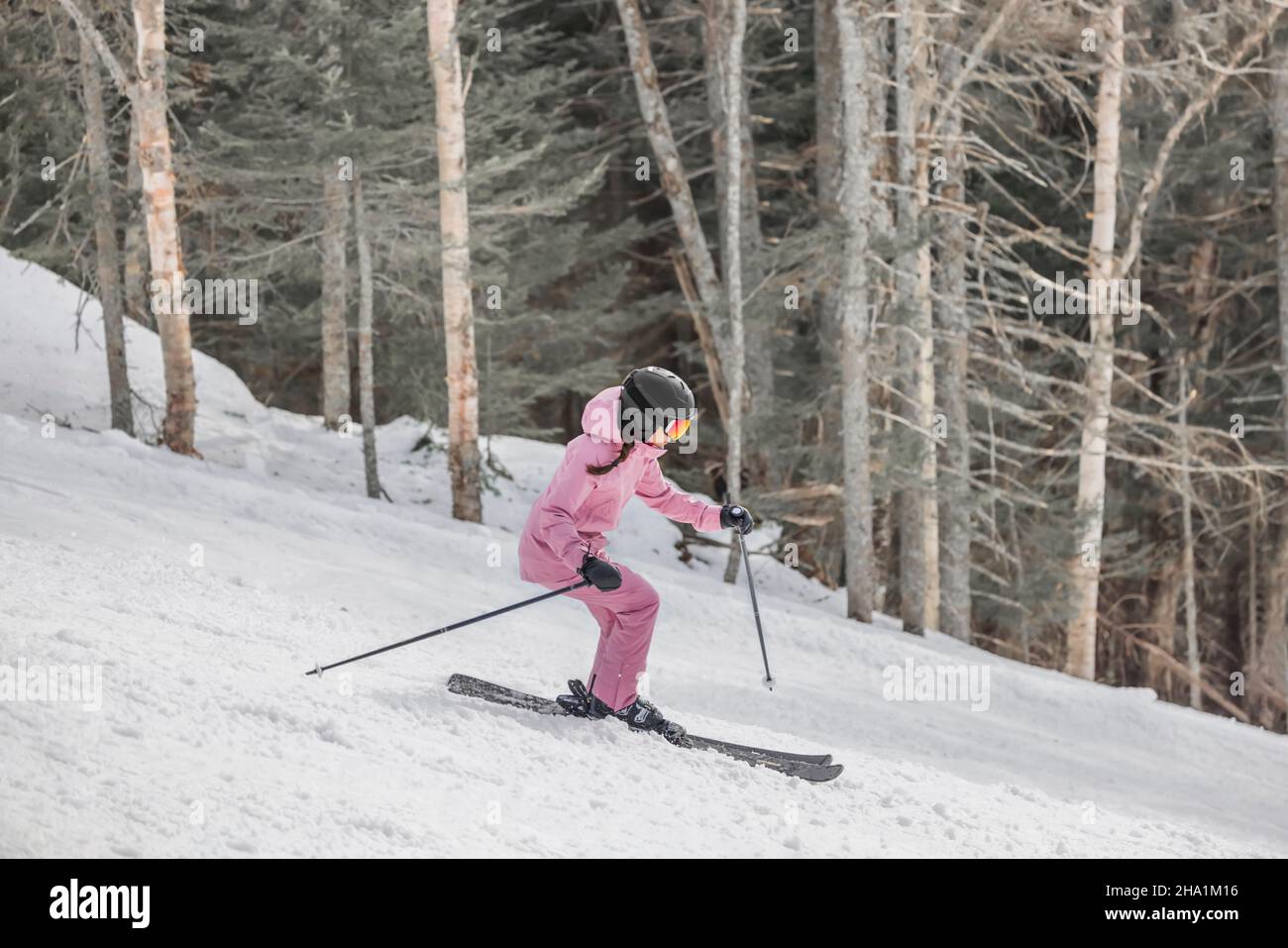 Downhillski Alpine Ski Foto. Frau beim Skifahren, die an einem verschneiten Tag Spaß auf der Piste hat - Wintersport und Aktivitäten. Coole Skibekleidung Stockfoto