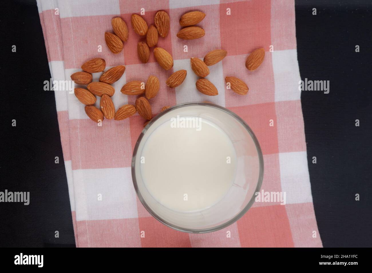 Vegane Mandelmilch auf dem Tisch mit Mandeln daneben gestreut. Stockfoto