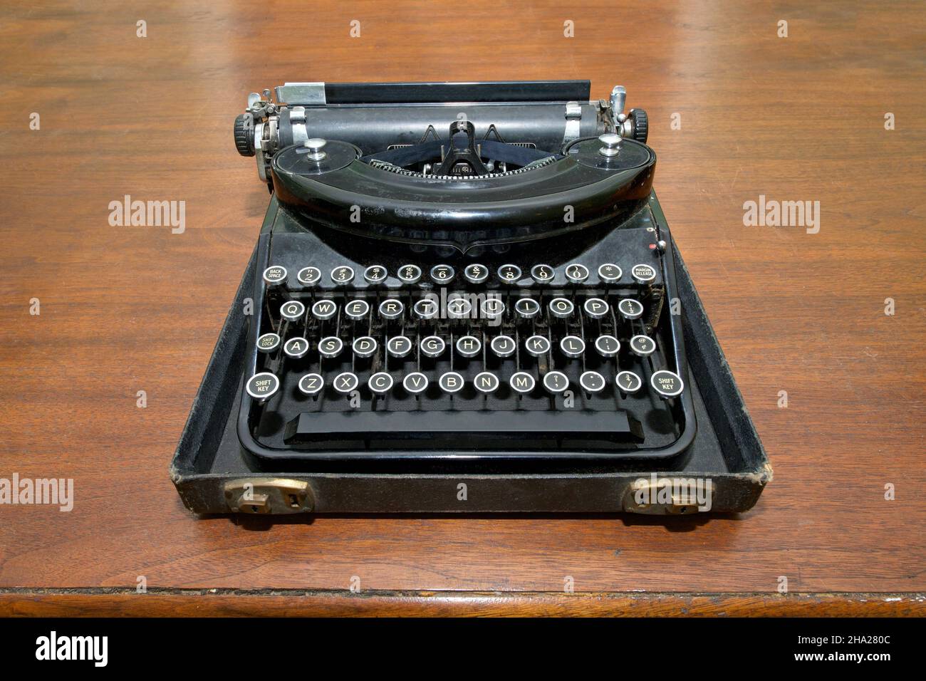 Antik getippter Schriftsteller, der in der unteren Hälfte der Tragetasche auf einem alten dunklen Holztisch sitzt. Vintage. Stockfoto
