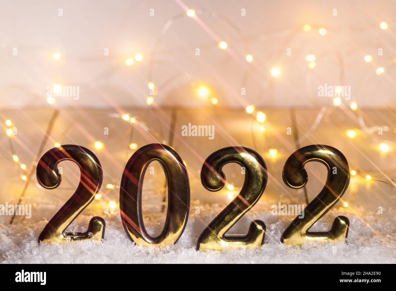 Goldnummern 2022 mit Schnee mit anamorphem Filter und leuchtender Girlande. Neujahr im Hintergrund mit 2022 Jahren Stockfoto