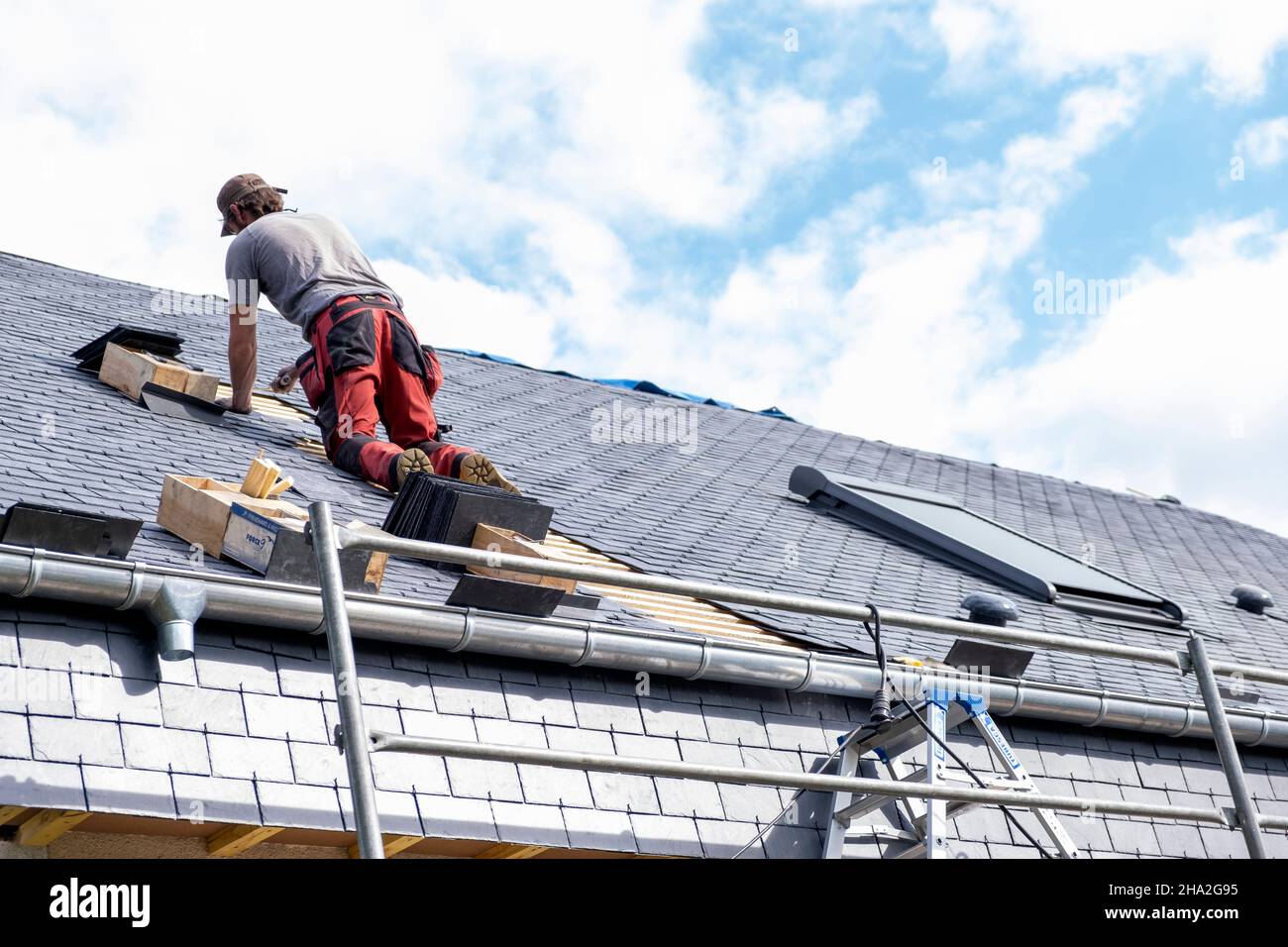 Renovierungsarbeiten, äußere Dachdämmung. Dachdecker spezialisiert auf Außenisolierung Verlegung von Schiefer auf dem Dach eines Hauses Stockfoto