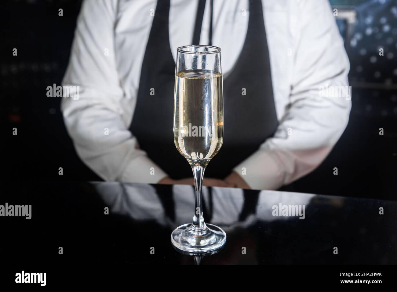 Ein Glas gekühltes alkoholisches Schaumgetränk mit Champagnergasen an der Theke vor dem Barkeeper, Nahaufnahme. Stockfoto