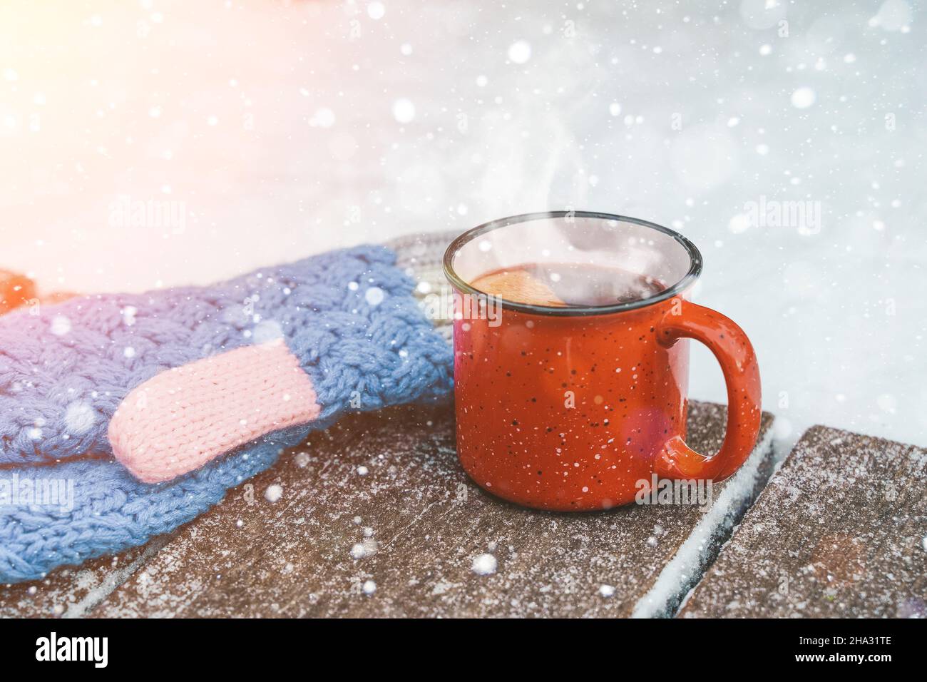 Glühwein oder Tee auf einem Holzhintergrund während eines Schneefalls im Wald. Warme Wintergetränke mit aromatischen Gewürzen von Zimt, Kardamom und Orange. Wärme, Komfort und Atmosphäre der Dezembernatur und Weihnachten. Hochwertige Fotos Stockfoto