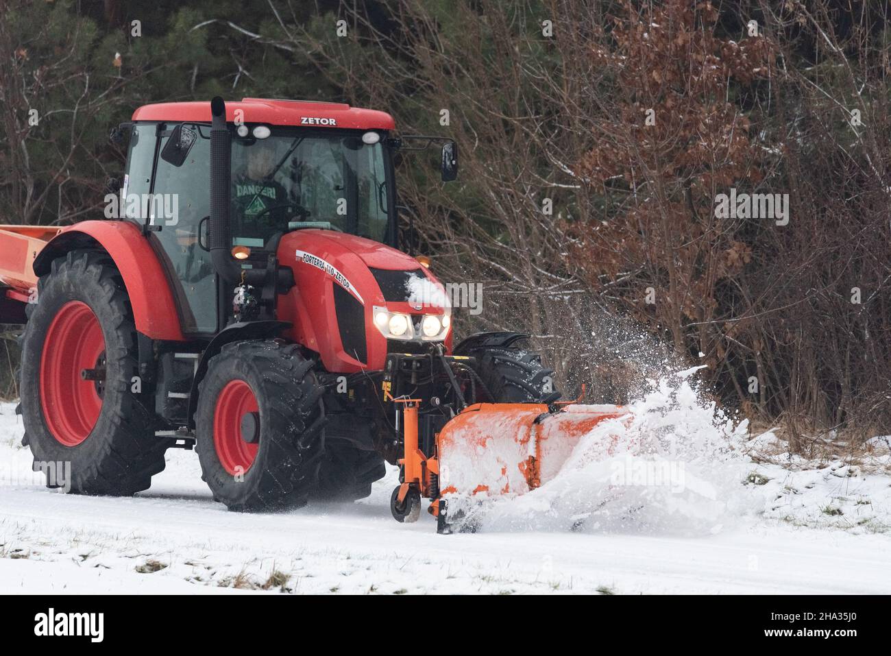 Pultusk, Polen - 10. Dezember 2021: Schneeräumung von einer Landstraße mit einem Traktor mit Schneepflug. Stockfoto