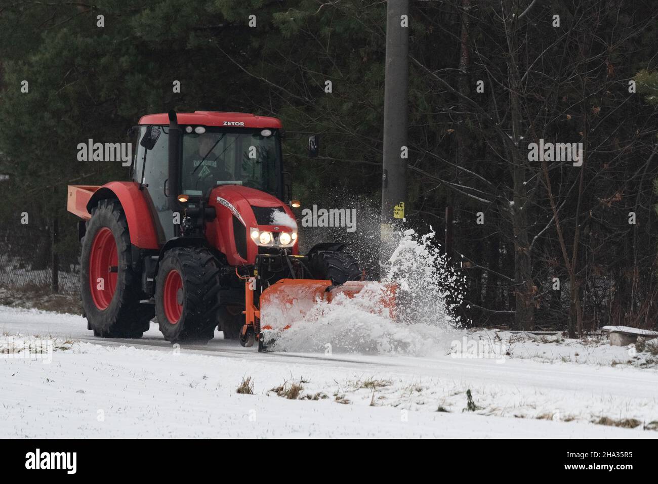 Pultusk, Polen - 10. Dezember 2021: Schneeräumung von einer Landstraße mit einem Traktor mit Schneepflug. Stockfoto