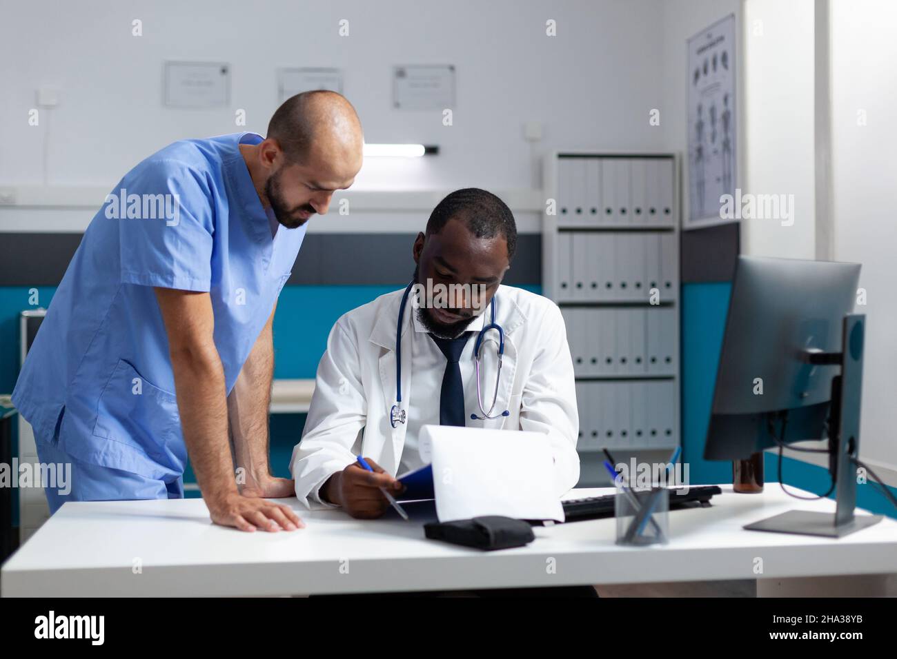 afroamerikanischer Arzt, der pharmazeutische Dokumente analysiert und über die Verschreibung von Medikamenten spricht, arbeitet bei der Behandlung im Krankenhaus. Therapeut Mann Krankenschwester Überwachung Krankheit Expertise Stockfoto