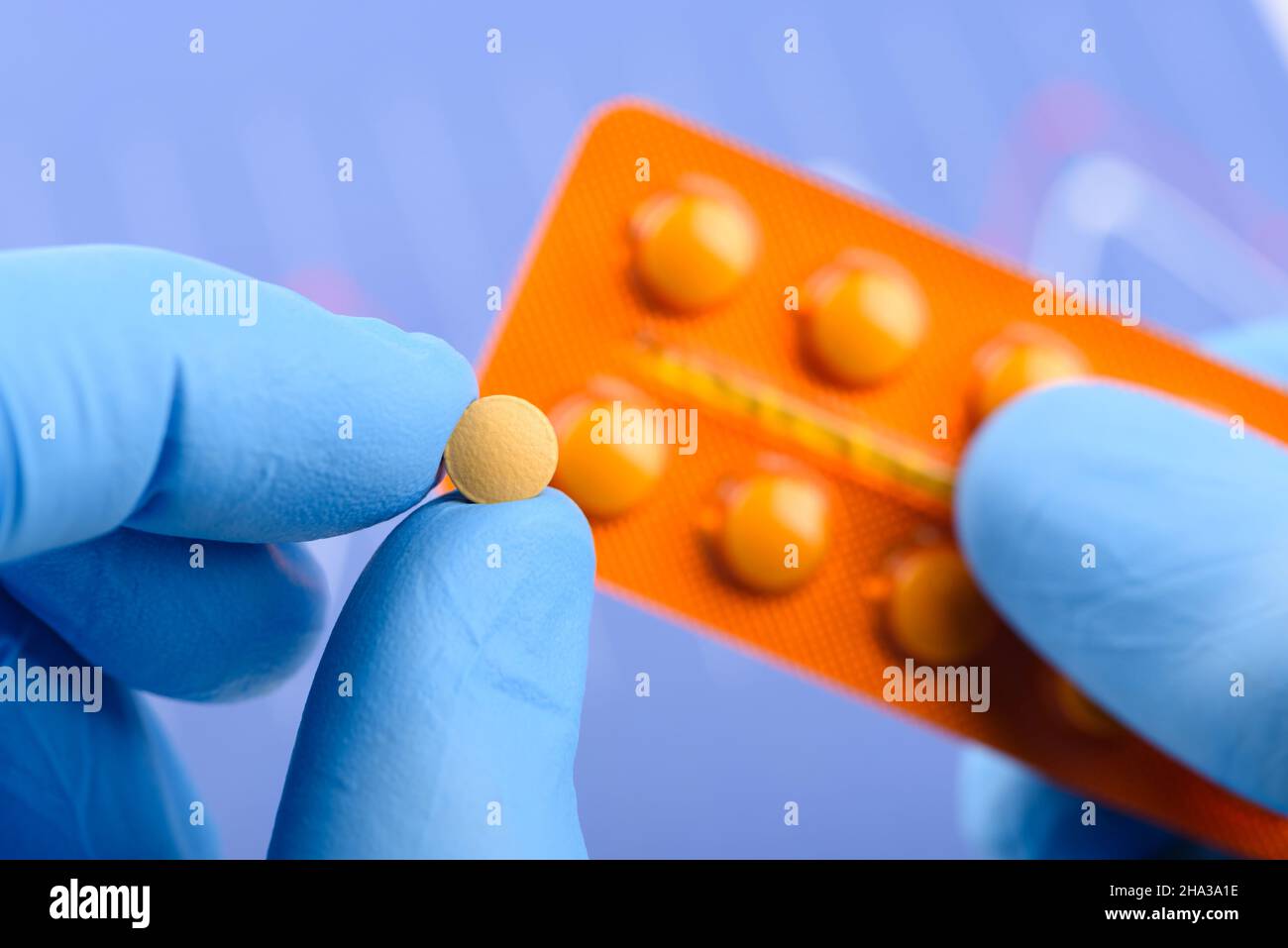 Wissenschaftler halten eine kleine Pille in der einen Hand und eine Blisterpackung in der anderen Stockfoto