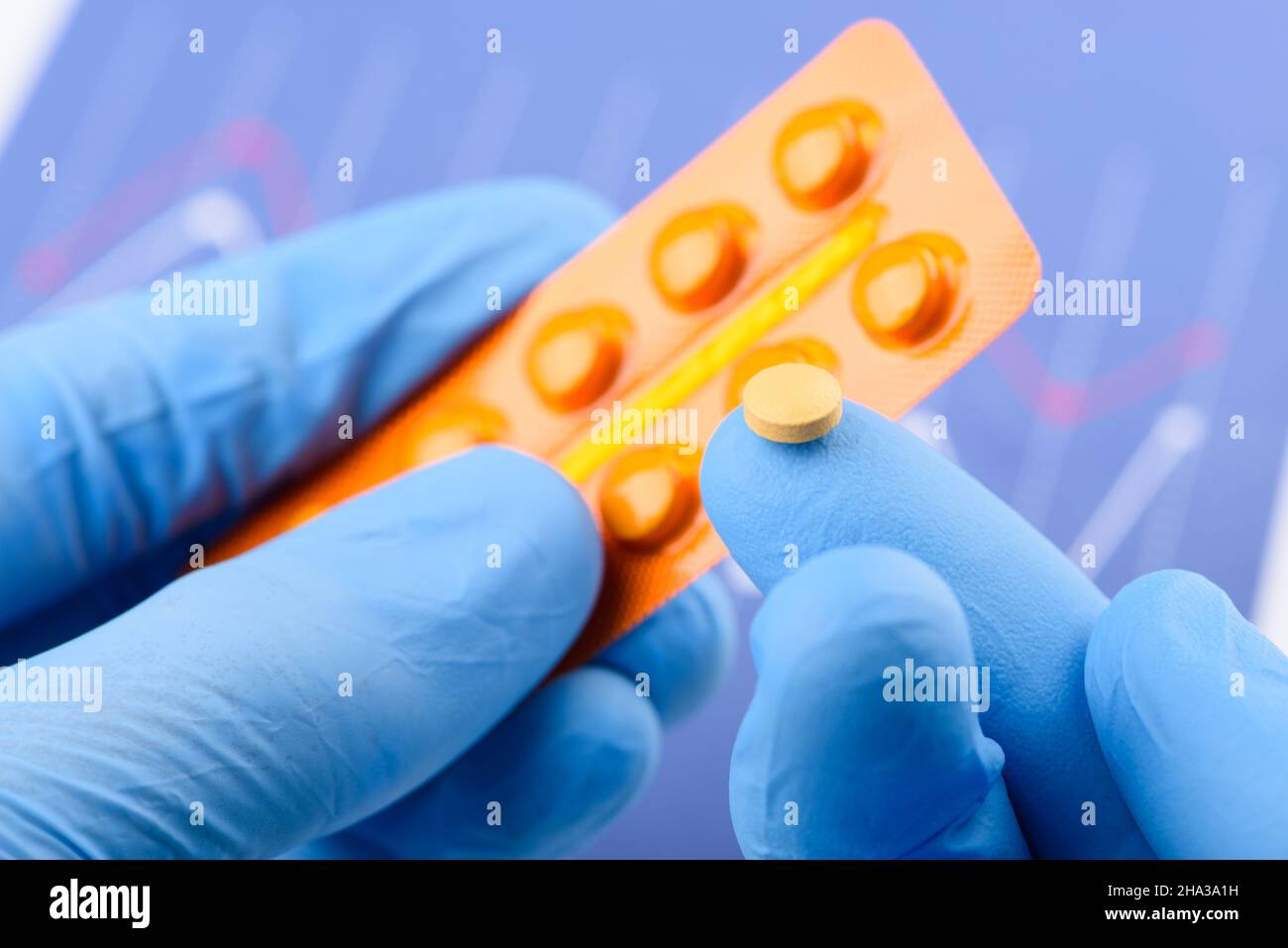 Wissenschaftler halten kleine Pille auf der Fingerspitze einer Hand und Blisterpackung in der anderen Stockfoto
