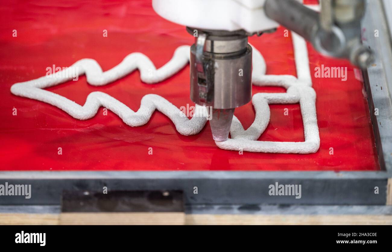 10. Dezember 2021, Sachsen, Chemnitz: Ein Roboter 3D druckt einen faserverstärkten Betonbogen in einer Forschungshalle der TU Chemnitz. Seit fünf Jahren forschen Wissenschaftler des Forschungsbereichs Leichtbau am Institut für Tragwerksplanung der Technischen Universität Chemnitz an automatisierten additiven Fertigungstechnologien. Kürzlich präsentierten sie den weltweit ersten 3D-gedruckten Beton-Schwibboden. Die Schwibbögen sind 120 Zentimeter breit, 60 Zentimeter hoch und wiegen 14 Kilogramm. Sie dienen als Referenzobjekte bei der Entwicklung innovativer Technologien für Th Stockfoto