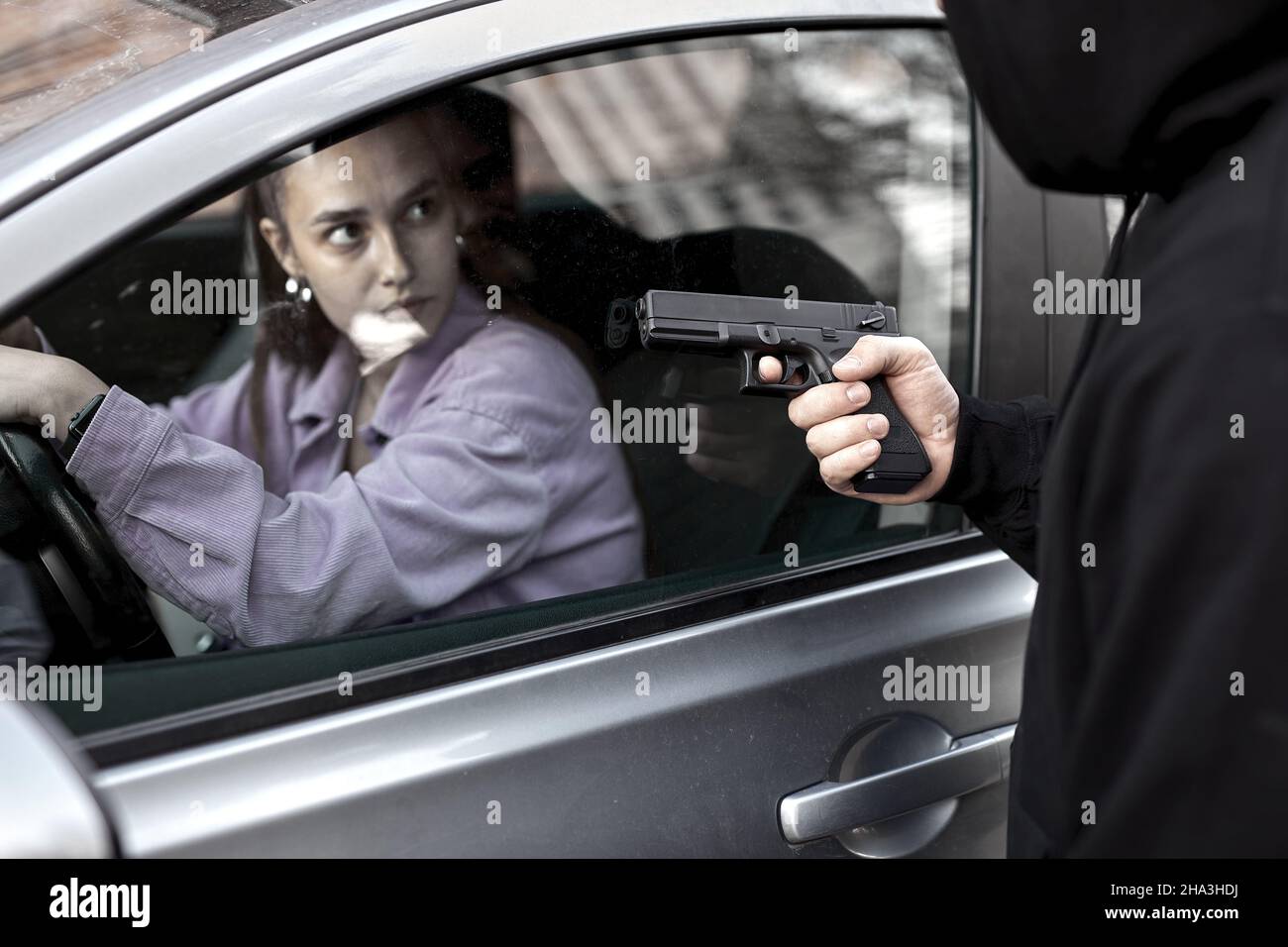 Bandit Mann Räuber hält Handfeuerwaffe Gangster zu entführen Geisel Frau Fahrer Auto schockiert und gefährlich auf Straße Gewalt Konzept. Seitenansicht auf Fr. Stockfoto
