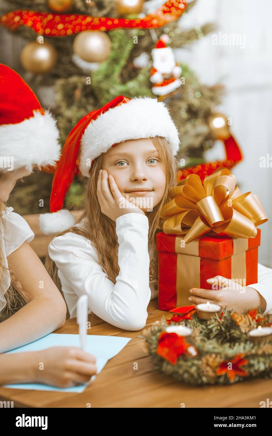 Kleine Schwestern Mädchen in Weihnachtsmäntel Schreiben Sie einen Brief an den Weihnachtsmann und genießen Sie Heiligabend. Hochwertige Fotos Stockfoto