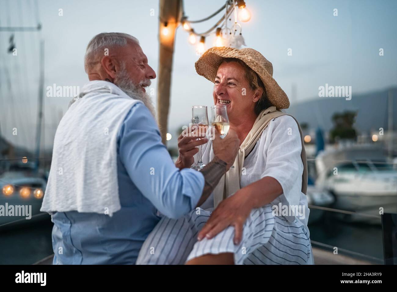Glückliches Seniorenpaar, das auf dem Segelboot Champagner toasten kann - romantische ältere Menschen, die auf einer Bootsfahrt den Hochzeitstag feiern Stockfoto
