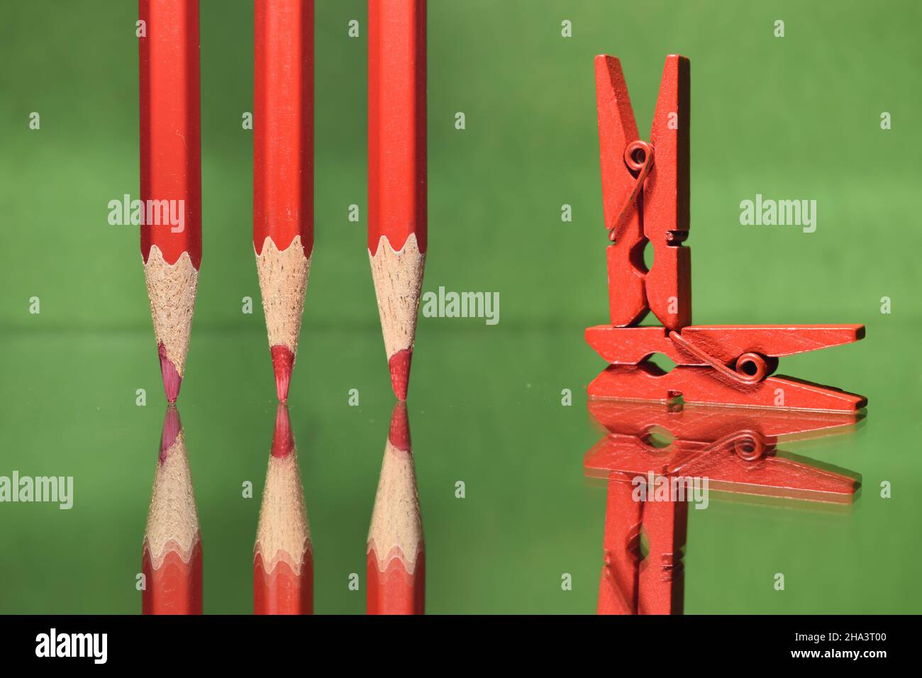 Rote Farbstifte und Fotoclips auf grünem Hintergrund. Stockfoto