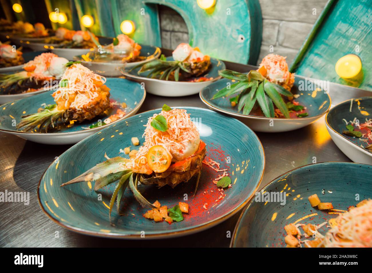 Frisch zubereiteter Salat liegt in der Ananas, die längs geschnitten und mit geriebenem Käse bestreut wird. Alles sieht sehr appetitlich aus. Stockfoto
