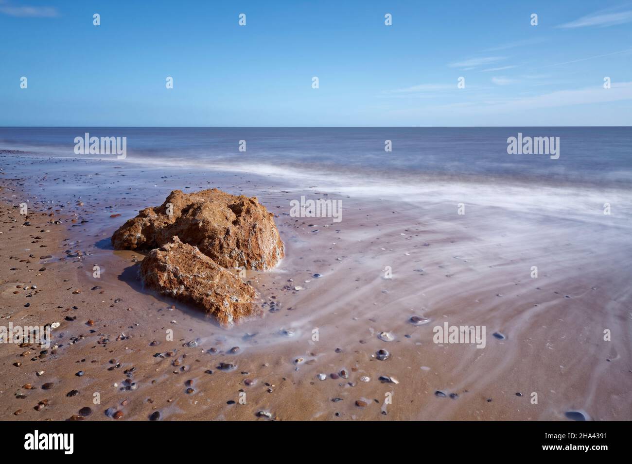 Ein Felsen am Strand, um den das Meerwasser fließt. Stockfoto