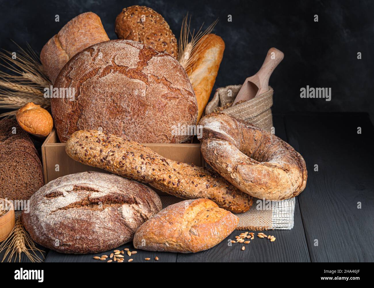Auswahl an frischem Roggen- und Weizenbrot auf dunklem Hintergrund. Seitenansicht, Kopierbereich. Stockfoto