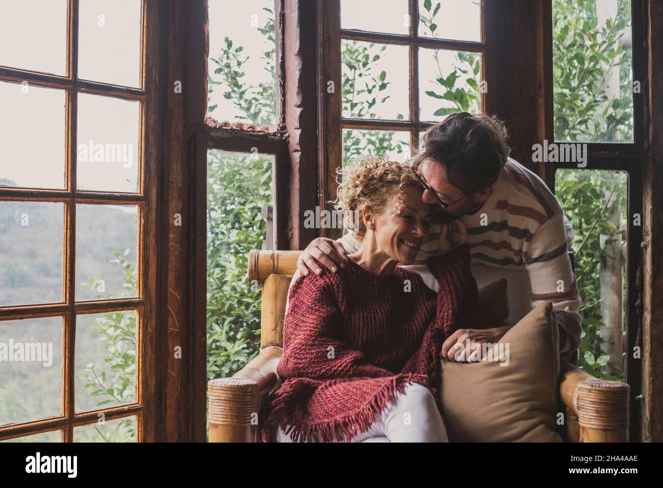 Glückliche Erwachsene Menschen ländlichen Lebensstil küssen und einander lieben. Frau auf der Couch sitzen und Mann küssen sie mit Zärtlichkeit. Herbst oder Wintersaison Leben im Freien Stockfoto