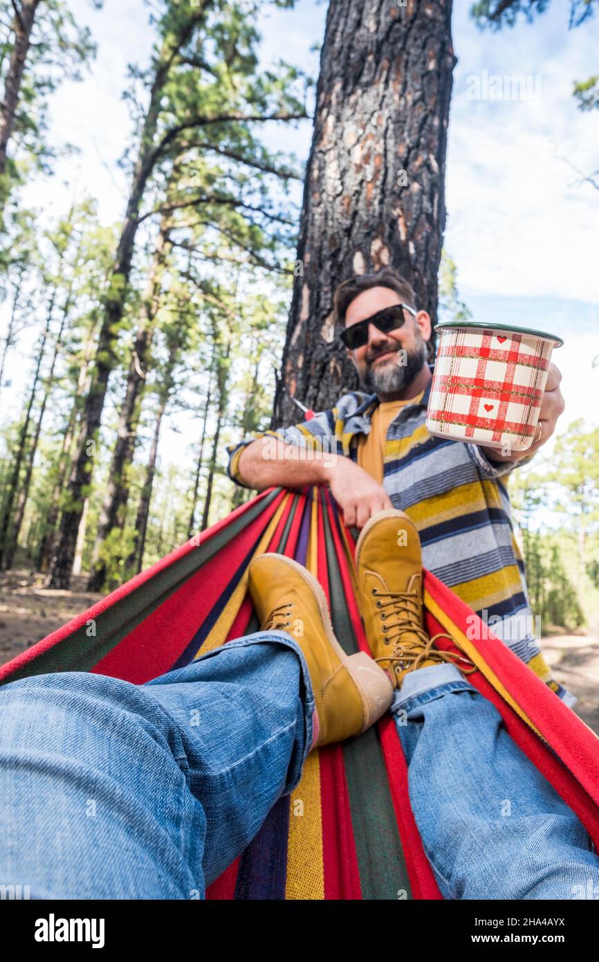 Glücklicher Erwachsener kaukasischen Paar genießen Sie die Natur Outdoor-Freizeit Camping-Aktivität - Frau Beine pov auf Hängematte und Mann mit Kaffee stehen - Umwelt und Natur Urlaub Stockfoto Glücklicher Erwachsener kaukasischen Paar genießen Sie die Natur Outdoor-Freizeit Camping-Aktivität - Frau Beine pov auf Hängematte und Mann mit Kaffee stehen - Umwelt und Natur Urlaub Stockfoto
